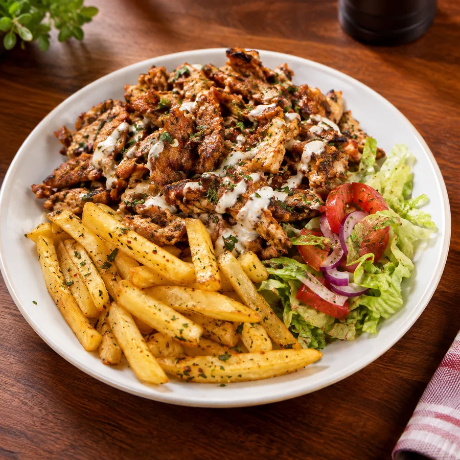 A plate of kebab with fries and salad